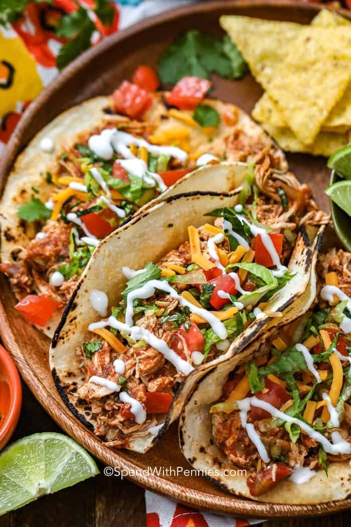 Crock-Pot chicken tacos on a wooden bowl with sour cream and cheese on top