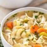 White bowl of chicken noodle soup with carrots