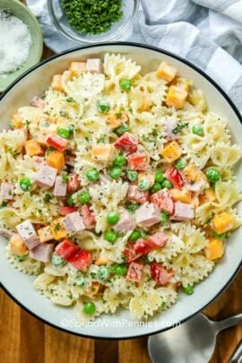 Bowtie pasta salad in a bowl with a serving spoon on the side