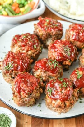 Meatloaf Muffins on a plate with vegetables in the background