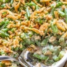 a cooked green bean casserole recipe in a white serving dish with a spoon