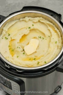 mashed potatoes in an Instant Pot with pats of butter and parsley as garnish