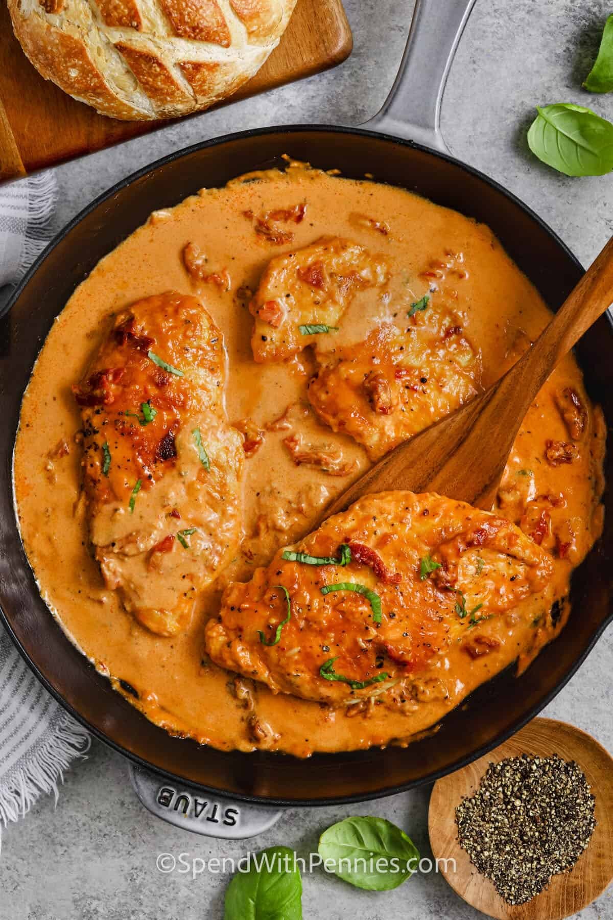 pan of Marry Me Chicken with a wooden spoon taking a piece out